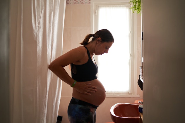 Pregnant woman touches her belly, in a story about signs you're dilating.
