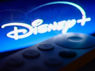 Disney+ logo on Chromecast menu displayed on a TV screen and Chromecast remote control are seen in t...