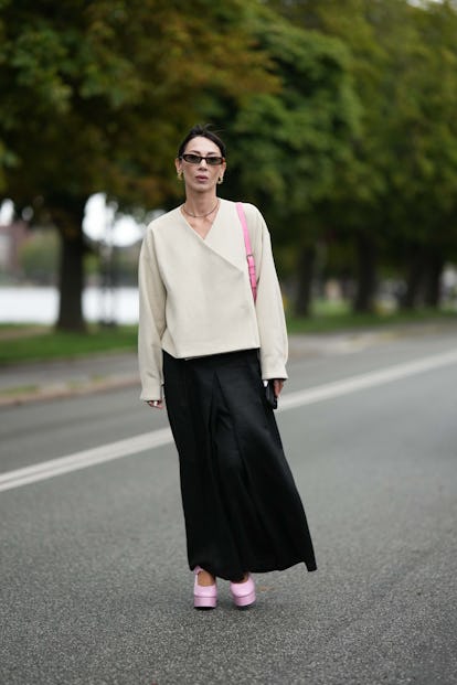 COPENHAGEN, DENMARK - AUGUST 09: A guest wears brown sunglasses, gold earrings, a black small pearls...