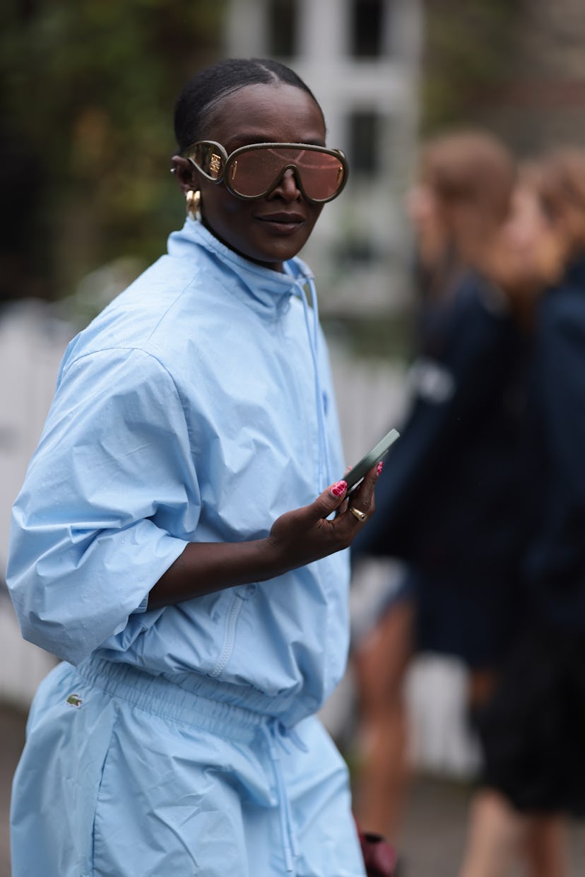 COPENHAGEN, DENMARK - AUGUST 09: A guest wears Loewe Wave Mask khaki green mirrored sunglasses, gold...