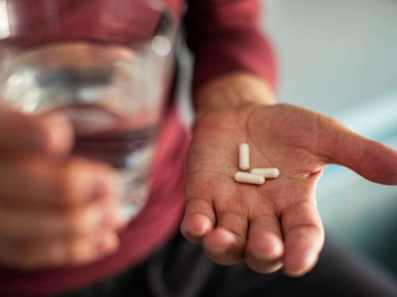 Close up of a senior man taking medicine in a bathroom