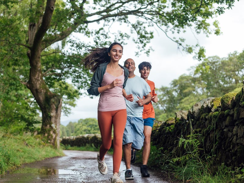 Front view full length of a mature father wearing sports clothing going for a run in the woods to ke...