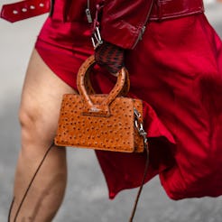 A close-up of a New York Fashion Week guest wearing a red shiny varnished leather zipper jacket and ...