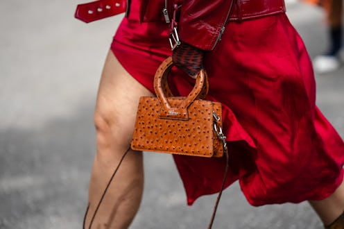 A close-up of a New York Fashion Week guest wearing a red shiny varnished leather zipper jacket and ...