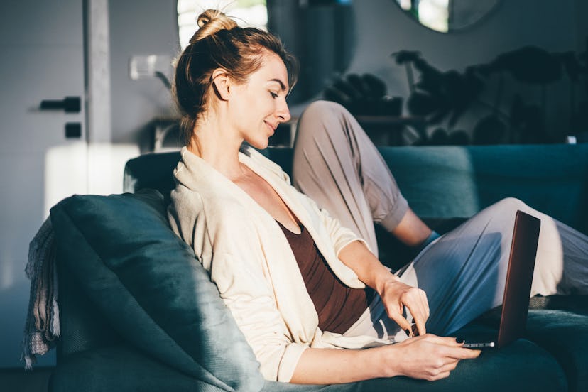 Woman Using Laptop On Sofa In Living Room.