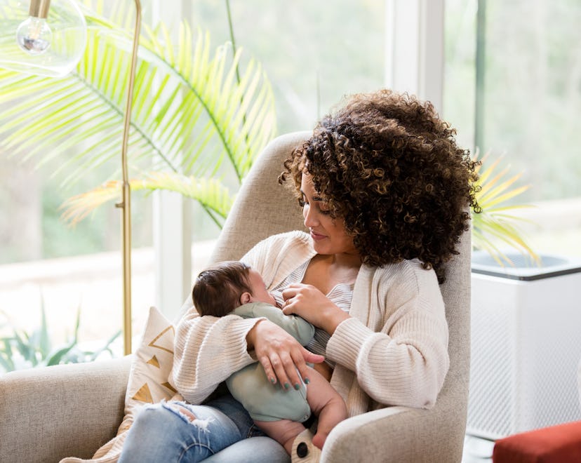 Young mom nurses her newborn baby while in the child's nursery.