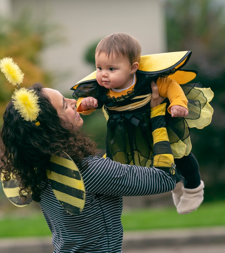 A beautiful mixed race mother in easy bumble bee costume holds her matching baby daughter up in the ...
