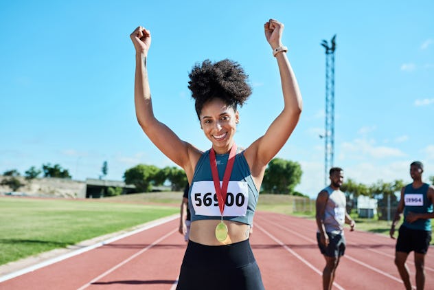 Woman sports runner, gold winner medal celebration and competitive win in track race performance. Wi...