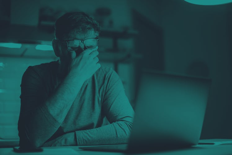 A man looks stressed out while looking at his laptop