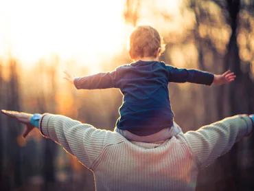 Picture of a grandfather playing with his three year old grandson in the park. The old man is wearin...