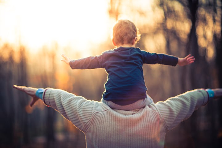 Picture of a grandfather playing with his three year old grandson in the park. The old man is wearin...