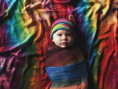 infant sleeping on rainbow sheets in article about rainbow baby day