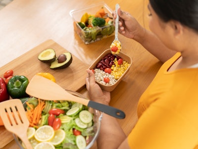 Cropped image of plus size woman having salad at dining table.