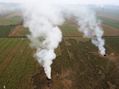 Aerial view of the white smoke clouds from burning paddy stubble in fields by farmers in Wanasari vi...