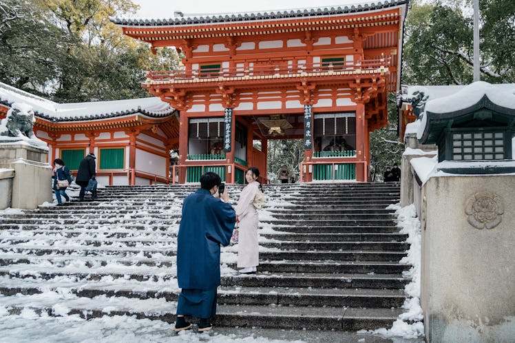 TOPSHOT - A woman poses for a photo on the snow-covered steps of the Yasaka Shrine in Kyoto on Janua...