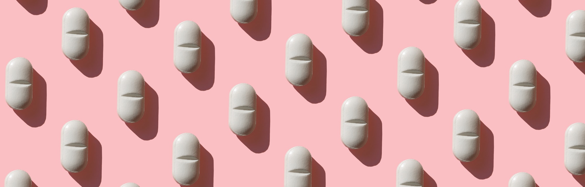 an image of a white pill on a pink background, in an article about zuranolone, the postpartum depres...