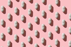 an image of a white pill on a pink background, in an article about zuranolone, the postpartum depres...
