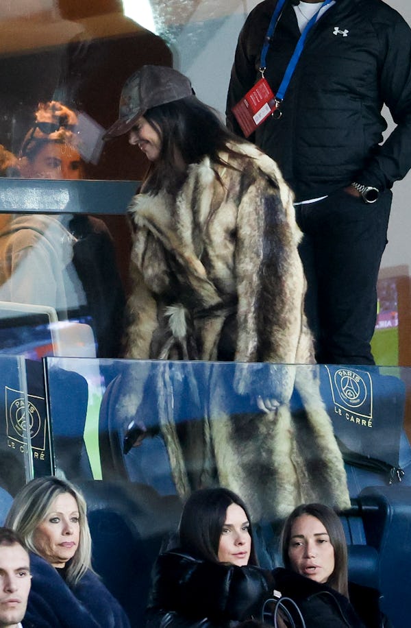 Kendall Jenner wears a camouflage print cap and fuzzy coat.