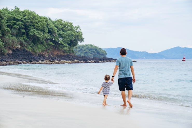 asian man teaching his baby walking on the beach