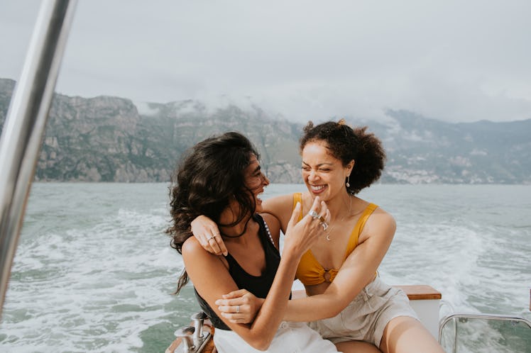 two young women embrace as they enjoy a boat ride, and consider how Jupiter retrograde 2023 will aff...