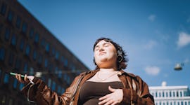 a young woman listening to music poses for a photo, as she considers how Jupiter retrograde 2023 wil...