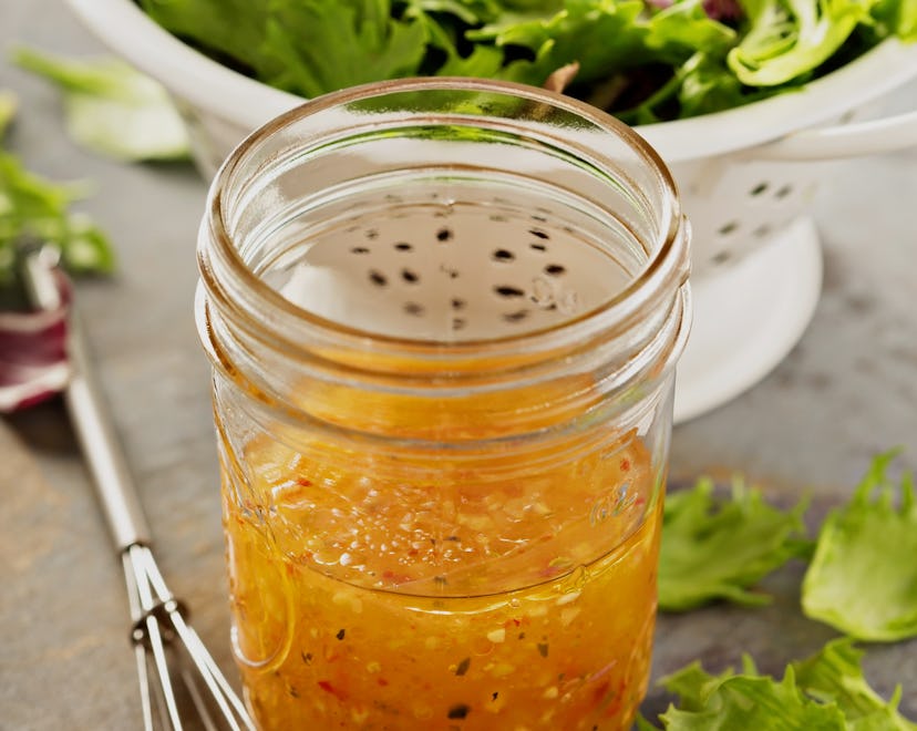 Italian vinaigrette dressing in a mason jar with fresh vegetables on the table