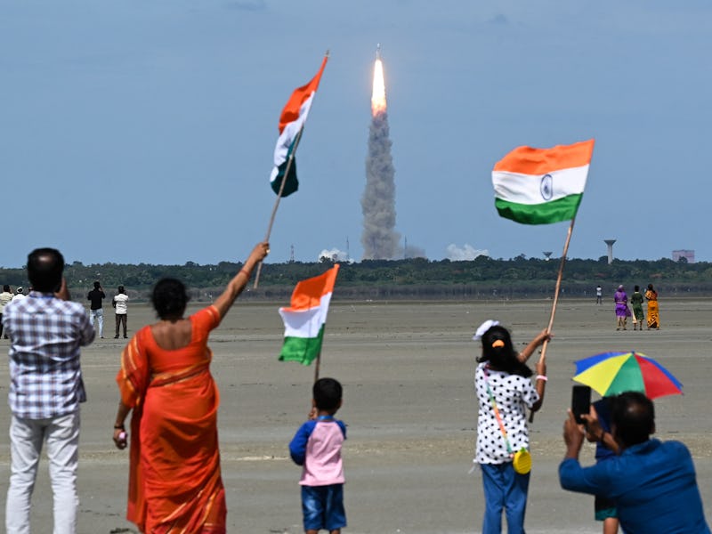 People wave Indian flags as an Indian Space Research Organisation (ISRO) rocket carrying the Chandra...