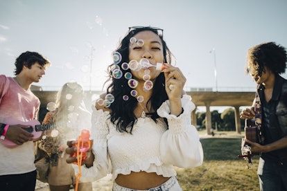 a young woman blows bubbles as she considers why September 3, 2023 will be the most romantic day for...