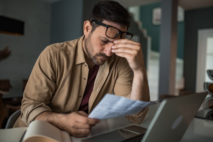 Overwhelmed young man paying taxes and bills at home on his laptop and not having enough.