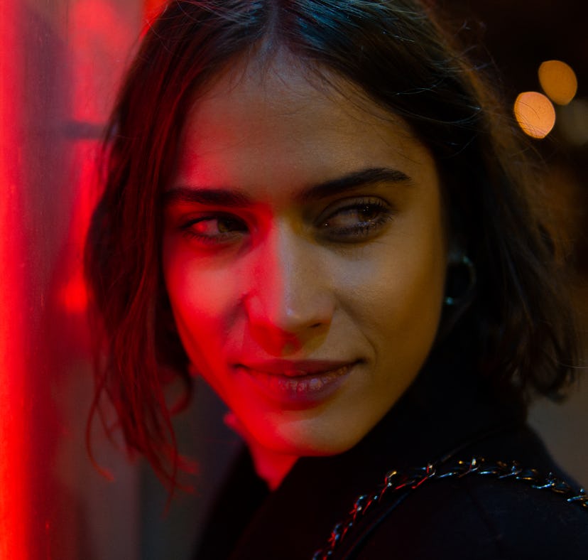 young woman poses under a red neon light as she considers why she keeps dating the same zodiac signs