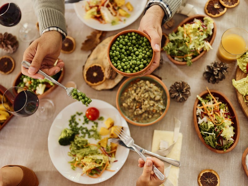 Close up of unrecognizable man serving beans to his wife during lunch at dining table.