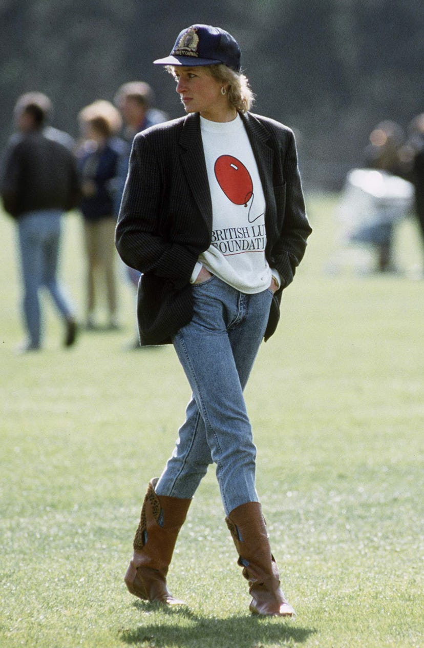 Princess Diana wears a sweatshirt with The British Lung Foundation logo, jeans, boots, and a basebal...