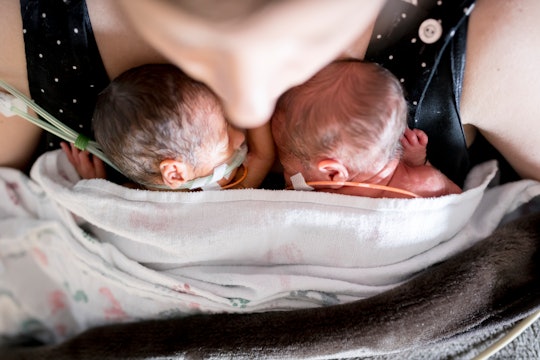 Mom holds newborn twins on her chest, in a story about twin birth videos and triplet birth videos.