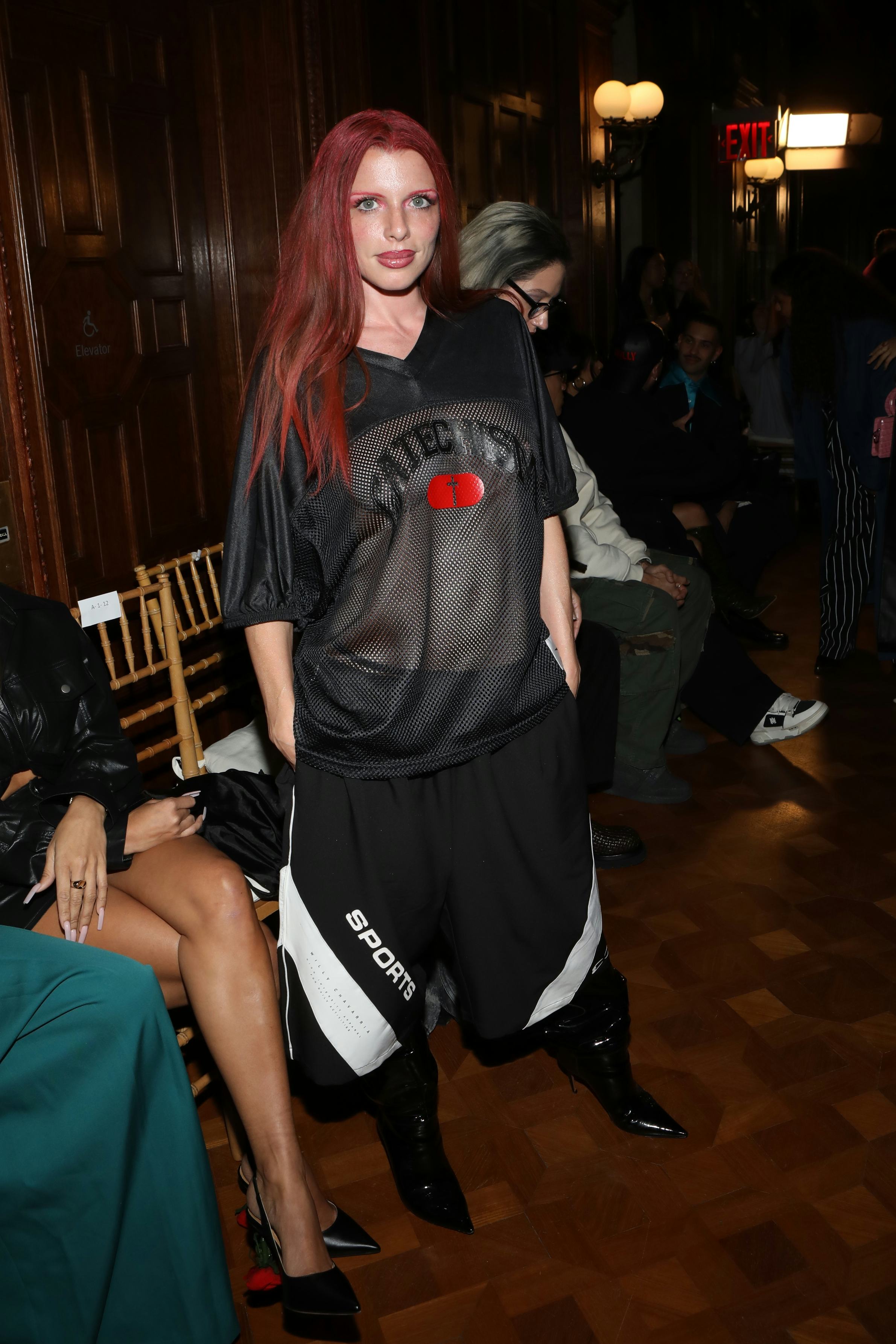 Julia Fox wears a net jersey top, oversized shorts, and black patent boots to NYFW.