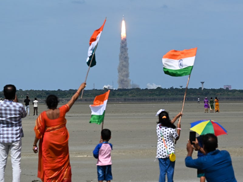 People wave Indian flags as an Indian Space Research Organisation (ISRO) rocket carrying the Chandra...