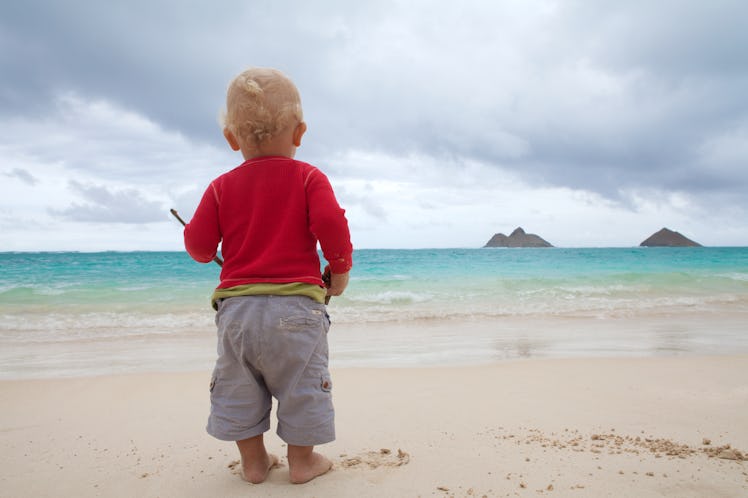 Toddler boy staring at sea.