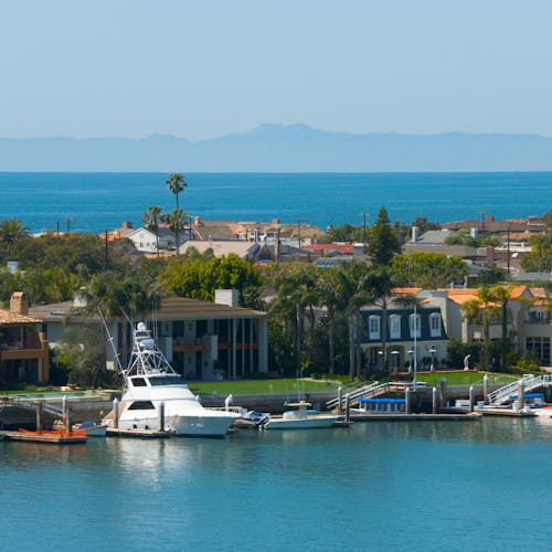 "A view of Newport Harbor in Newport Beach, CA, with Balboa Island in the Foreground, and the Ocean ...