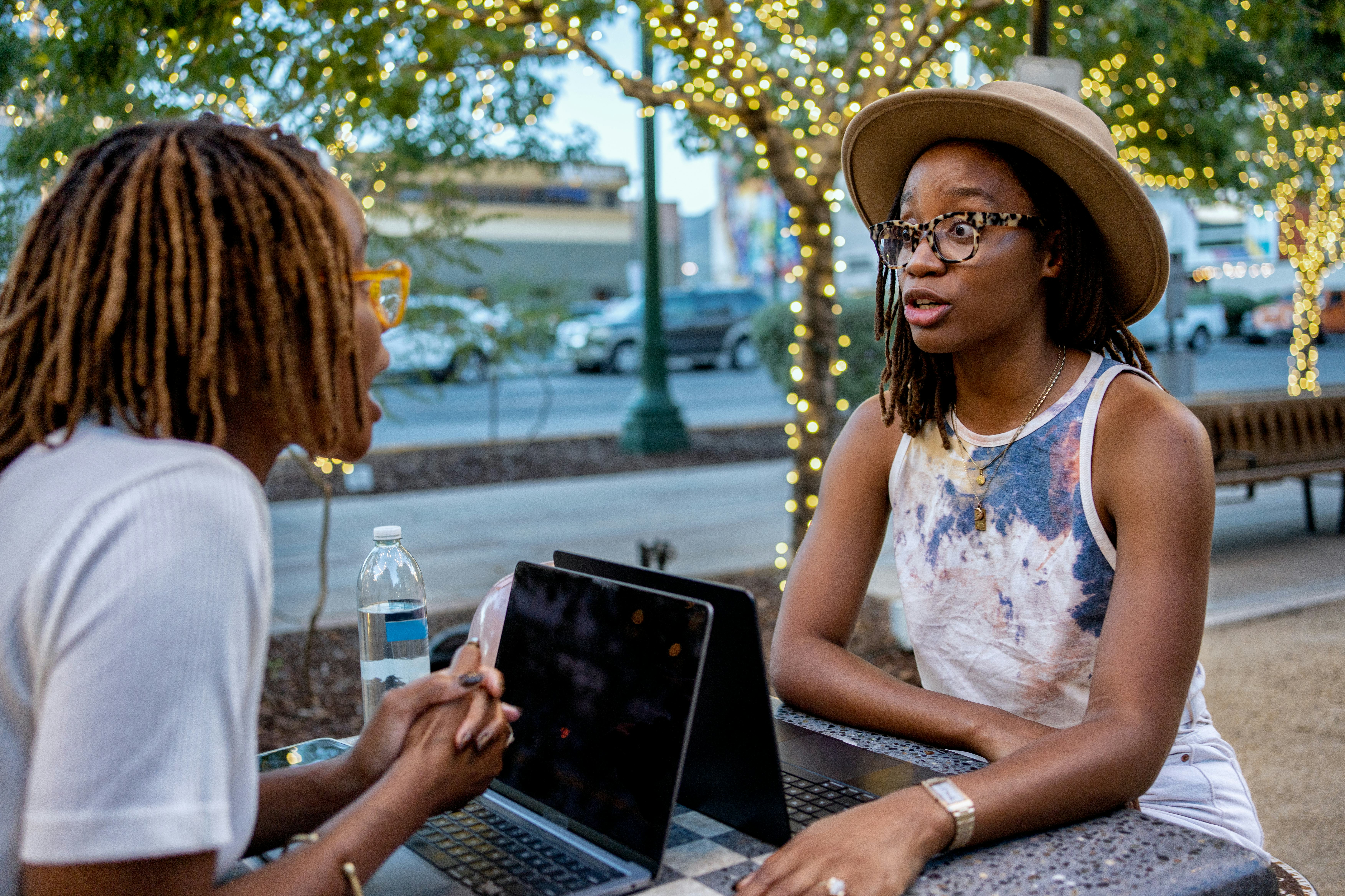 Two African-American Twin Sisters in Their Twenties Enjoying a Deep Conversation at a Table in a Pub&hellip;