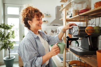 young woman makes a coffee in her home, as she considers her fall equinox 2023 horoscope