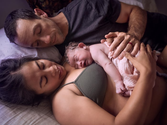 A mother holds her just born baby on her chest at home, in a list of home birth videos that are real...