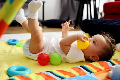 Baby girl plays with toys, in an article about why babies shake their heads back and forth