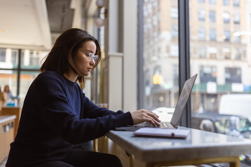 In this captivating photo, an Asian female student finds solace in a cozy Soho café, immersed in her...