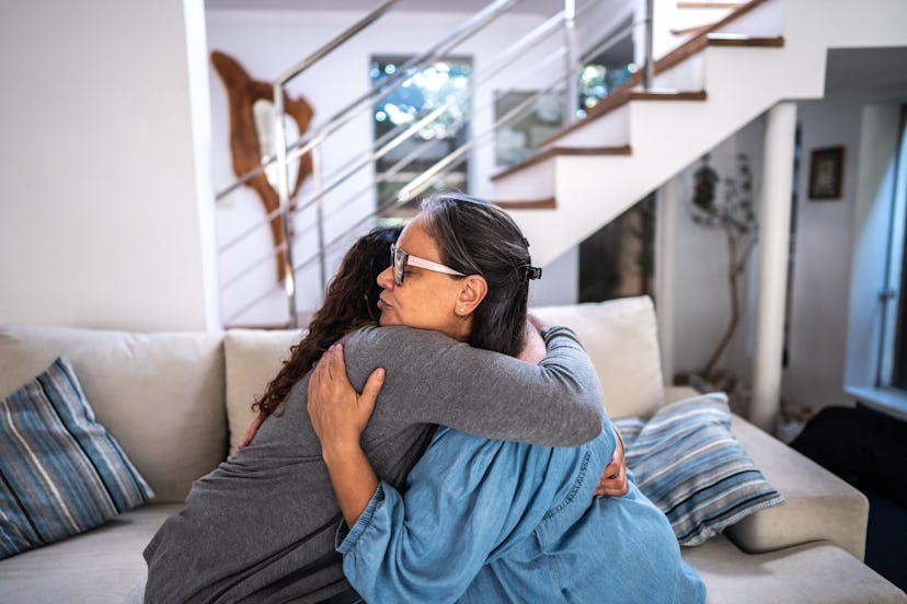 Sadyoung woman embracing her mother in the living room at home