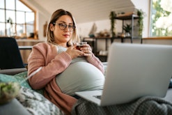 Young pregnant woman drinking tea at home, in a story answering the question, is lasik safe during p...