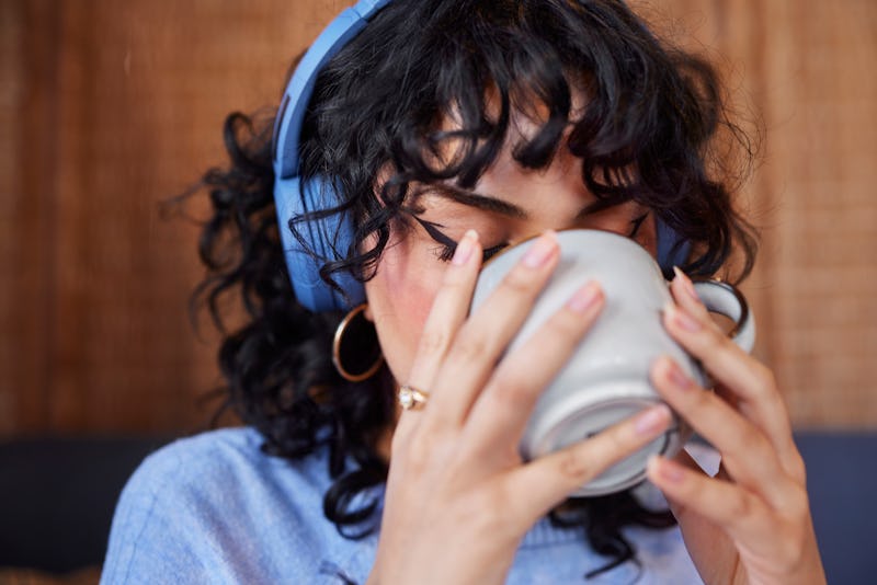 Young woman in headphones drinking coffee