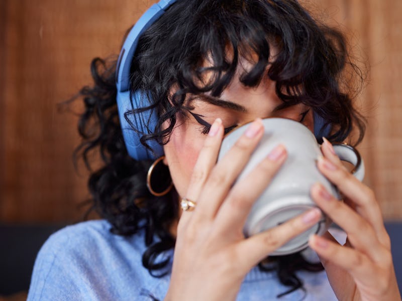 Young woman in headphones drinking coffee