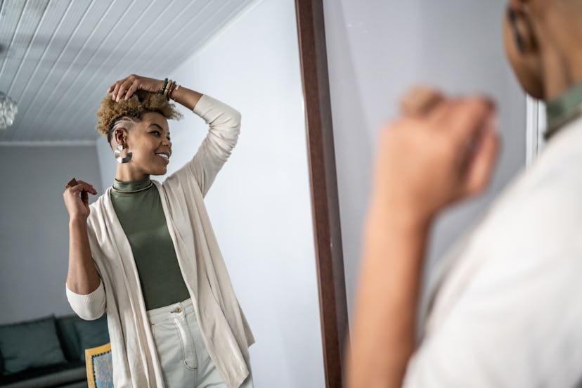 Mid adult woman looking at herself in the mirror at home