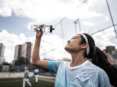Female soccer player washing face in the field
