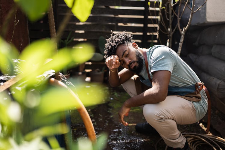 A tired young man is working in his garden