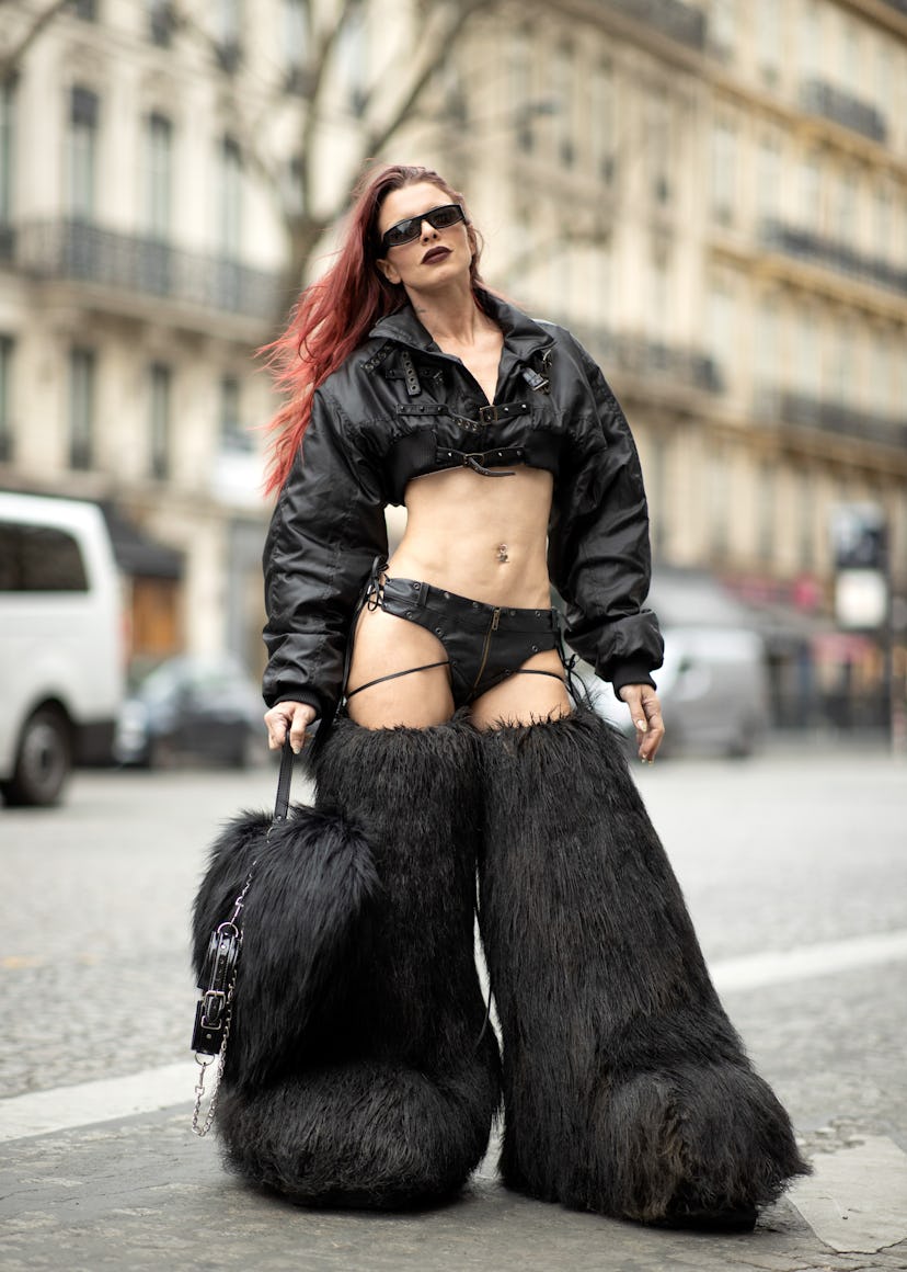 Julia Fox wears a black crop jacket, thong, and fuzzy boots.